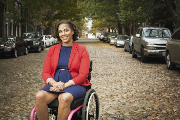 Disabled woman smiling in wheelchair on cobblestone street