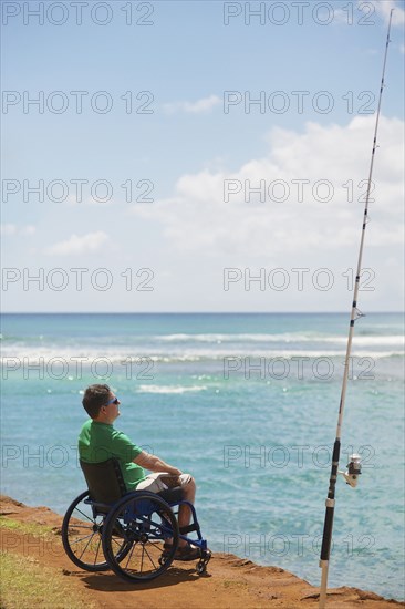 Disabled man in wheelchair fishing on beach