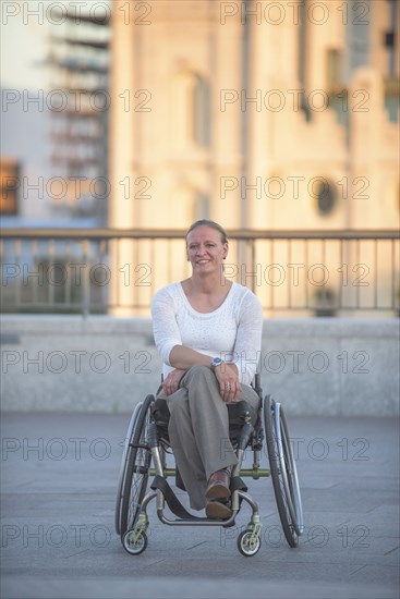 Disabled woman sitting in wheelchair on urban rooftop