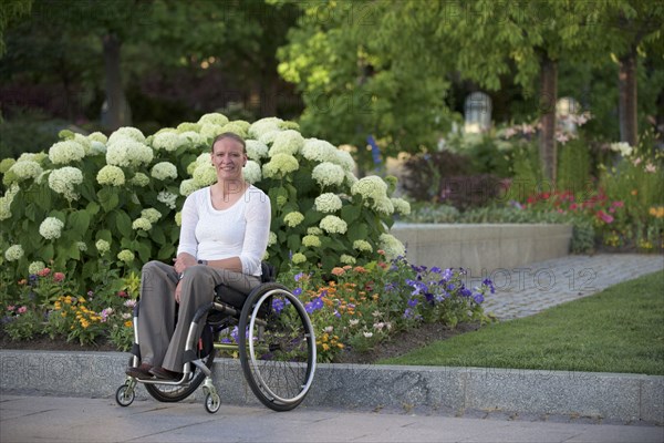 Disabled woman sitting in wheelchair on city street