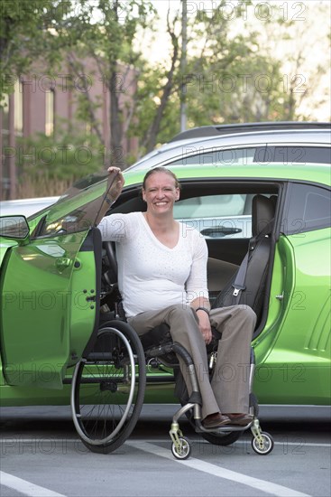 Disabled woman in wheelchair climbing into car