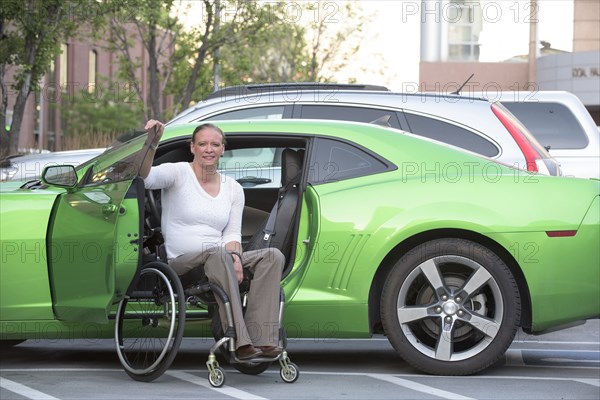 Disabled woman in wheelchair climbing into car