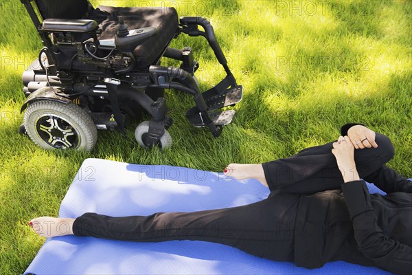 High angle view of disabled woman stretching legs in park
