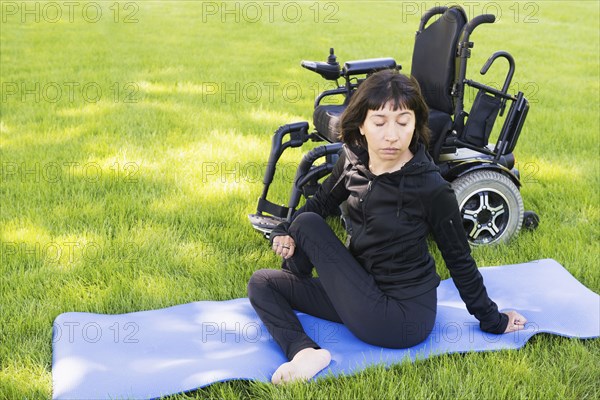 Disabled woman stretching legs in park