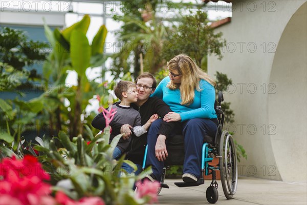 Paraplegic woman and family hugging in garden