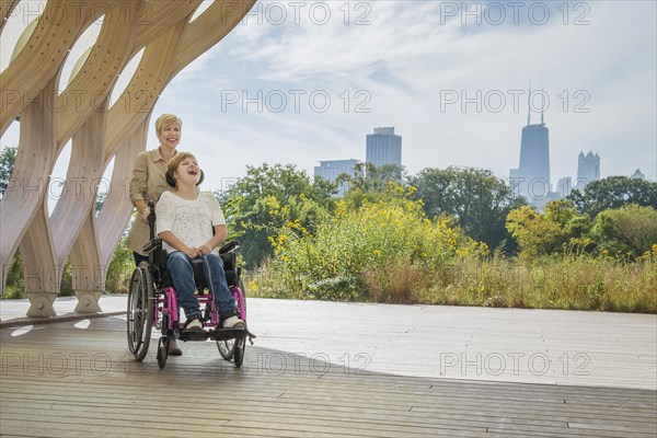 Mother pushing paraplegic daughter in wheelchair