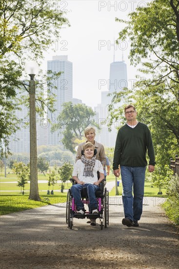 Parents pushing paraplegic daughter in wheelchair