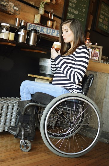 Paraplegic woman in wheelchair drinking coffee