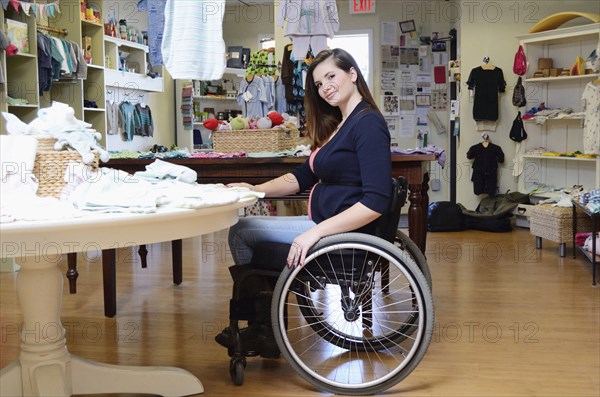 Pregnant paraplegic woman in wheelchair shopping in baby store