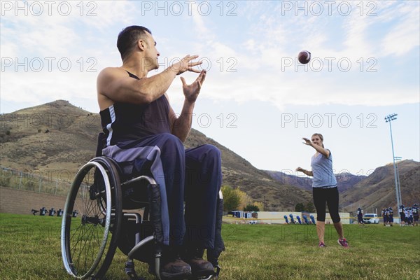 Paraplegic athlete in wheelchair with girlfriend tossing ball