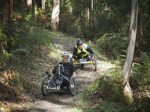 Men riding modified bicycles on forest path