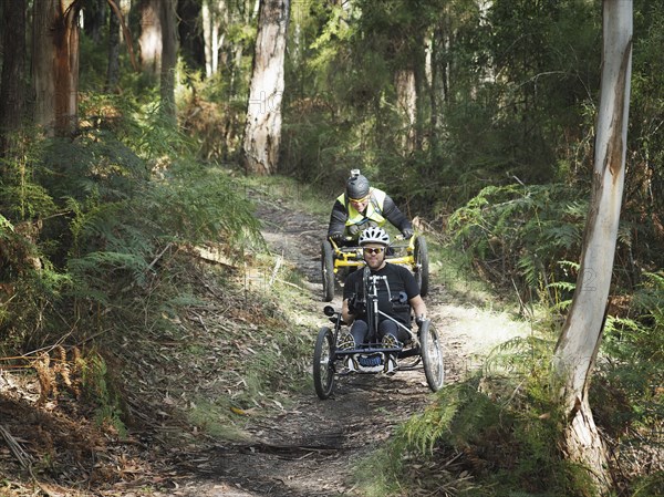 Men riding modified bicycles on forest path