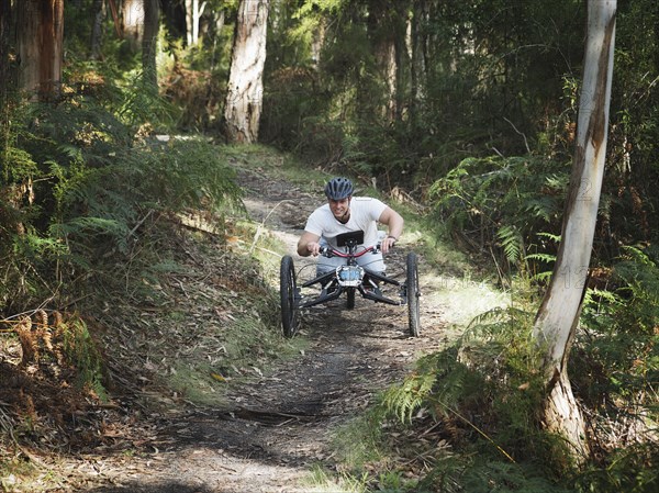 Man riding modified bicycles on forest path