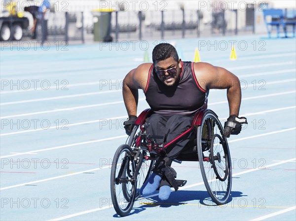 Middle Eastern man racing in wheelchair on track