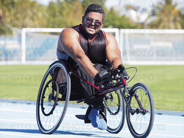 Middle Eastern man racing in wheelchair on track