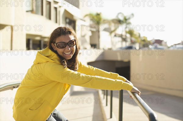 Mixed race woman in sunglasses leaning on railing