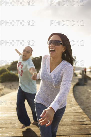 Couple holding hands and walking on boardwalk