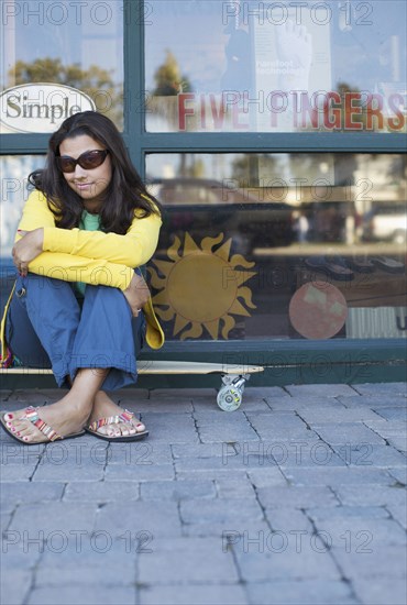 Mixed race woman sitting on skateboard