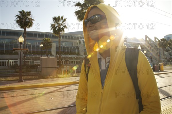 Mixed race woman in hoody and sunglasses walking