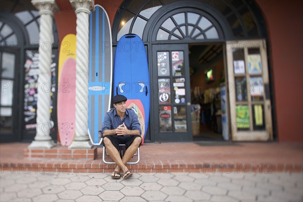 Mixed race business owner sitting outside store