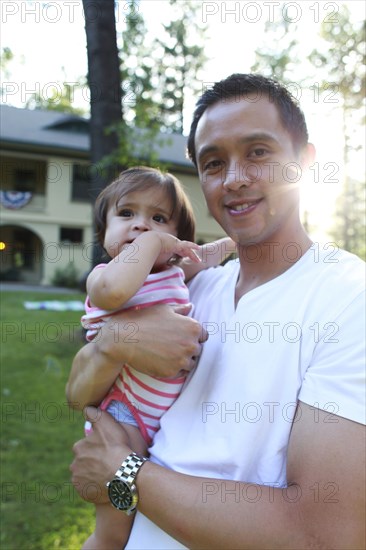 Father holding daughter outdoors