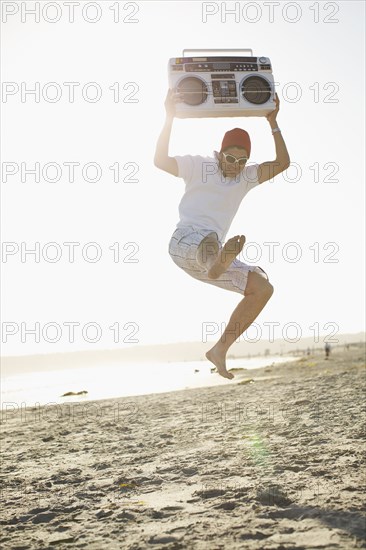 Hispanic man holding boom box and jumping