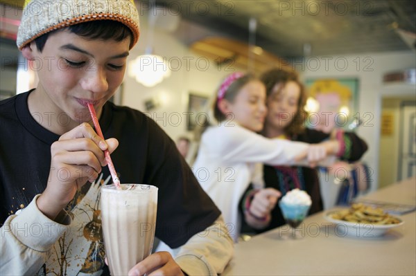 Mixed race boy drinking milkshake in cafe