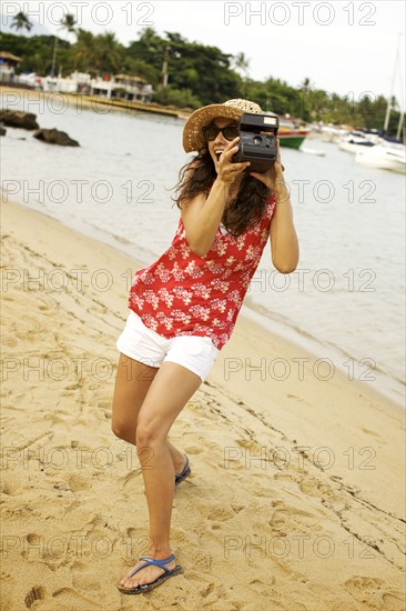 Mixed race woman on beach with camera