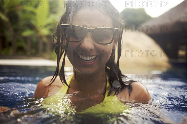 Mixed race woman wearing sunglasses in swimming pool