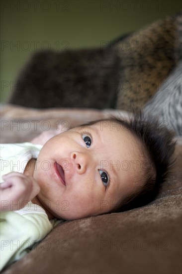 Mixed race newborn baby laying on blanket