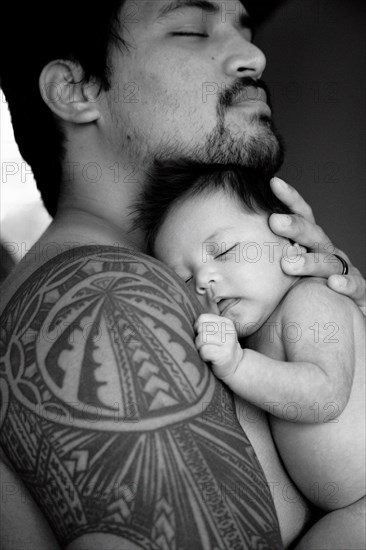 Tattooed father holding newborn baby