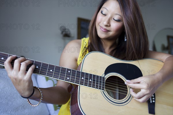 Mixed race teenage girl playing guitar