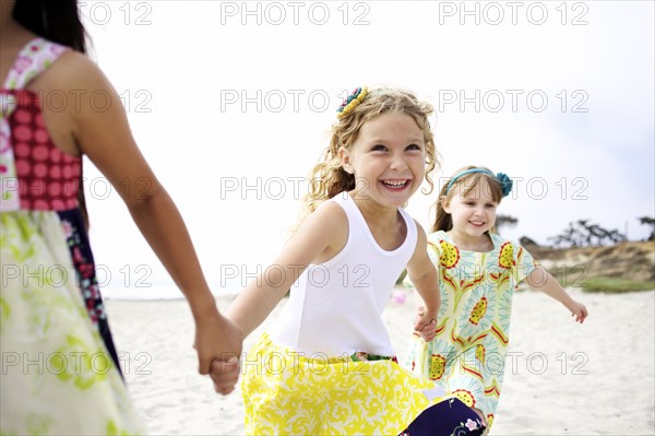 Children holding hands running on beach