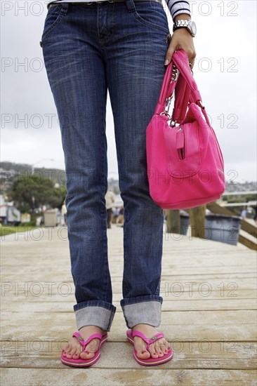 Hispanic woman on boardwalk in flipflops and carrying purse