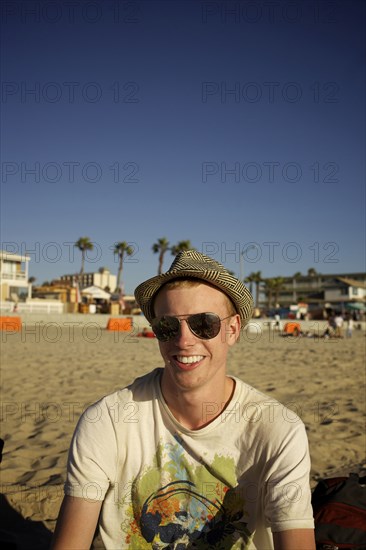 Smiling Caucasian man sitting on beach