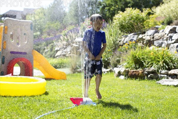 Caucasian boy playing in backyard sprinkler