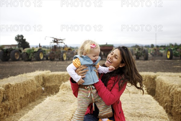 Mother and daughter enjoying playing on hay bales