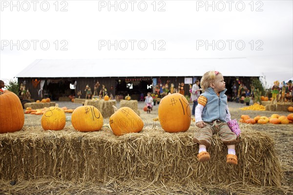 Caucasian girl sitting with pumpkins in pumpkin patch