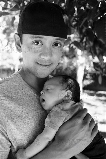 Father holding newborn baby outdoors