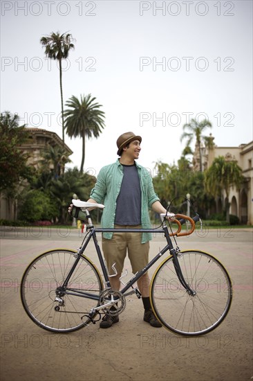 Pacific Islander man standing with bicycle