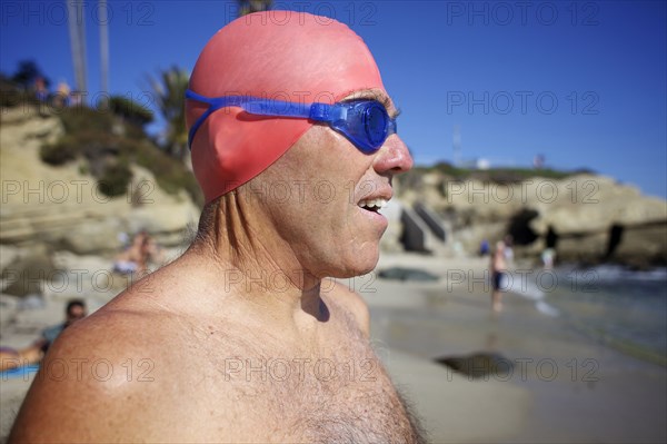 Man in swim cap and goggles on beach