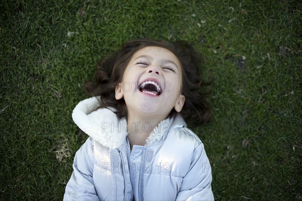 Laughing mixed race girl laying in grass