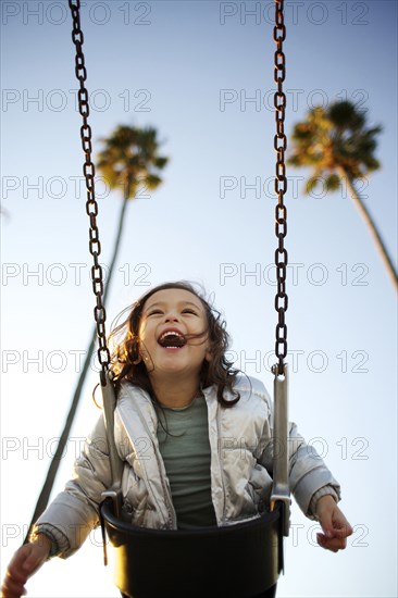 Laughing mixed race girl swinging