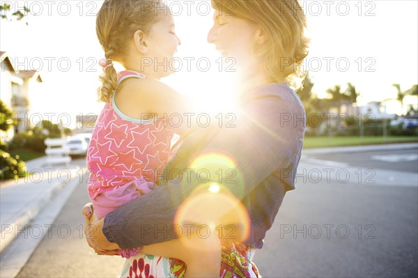 Mother holding daughter in street