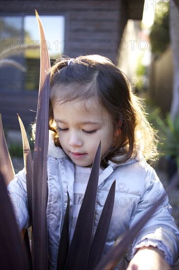 Mixed race girl looking at plant