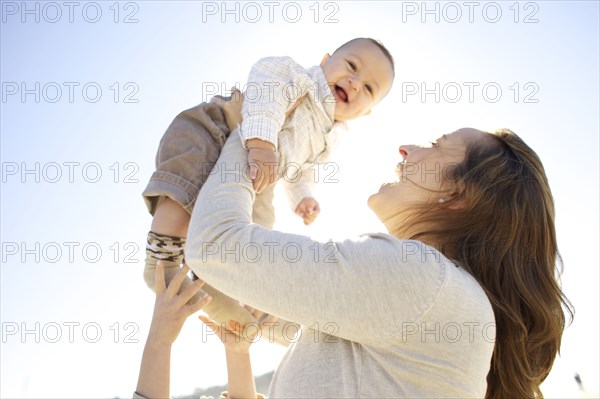 Mother lifting baby outdoors