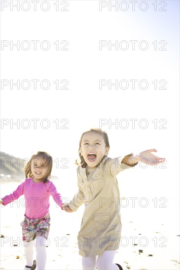 Mixed race girls running on beach