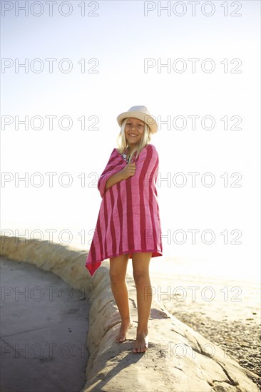 Mixed race girl at beach wrapped in towel