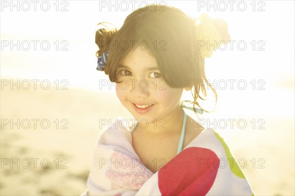 Mixed race girl on beach wrapped in towel