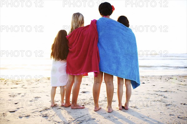 Girls wrapped in towels standing on beach